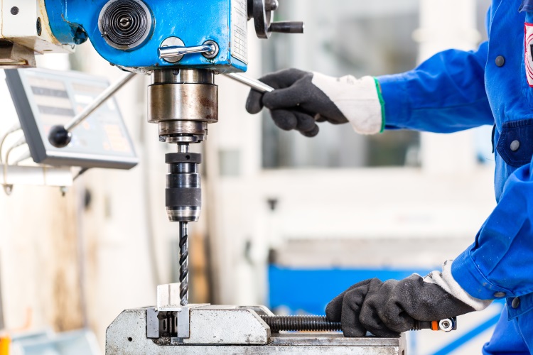 Craftsman drilling metal with drill in workshop