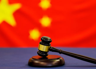 Judge's gavel. Symbol for jurisdiction. Law concept a wooden judges gavel on table in a courtroom or law enforcement office on blue background. China flag background