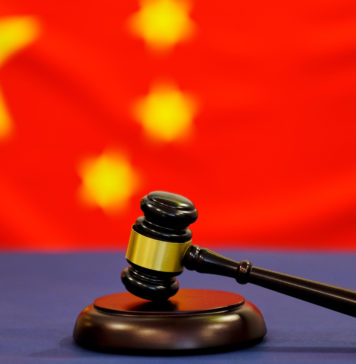 Judge's gavel. Symbol for jurisdiction. Law concept a wooden judges gavel on table in a courtroom or law enforcement office on blue background. China flag background