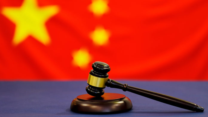 Judge's gavel. Symbol for jurisdiction. Law concept a wooden judges gavel on table in a courtroom or law enforcement office on blue background. China flag background