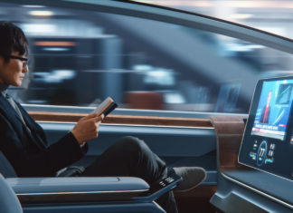 Futuristic Concept: Businessman in Glasses Reading Notebook and Watching News on Augmented Reality Screen while Sitting in a Autonomous Self-Driving Zero-Emissions Car.