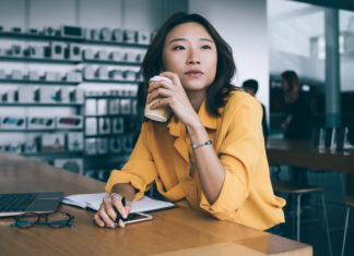 Asian woman drinking coffee and thinking at desk