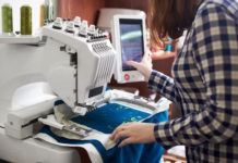 Close-up of woman working on modern computerized embroidery machine creating green floral pattern.